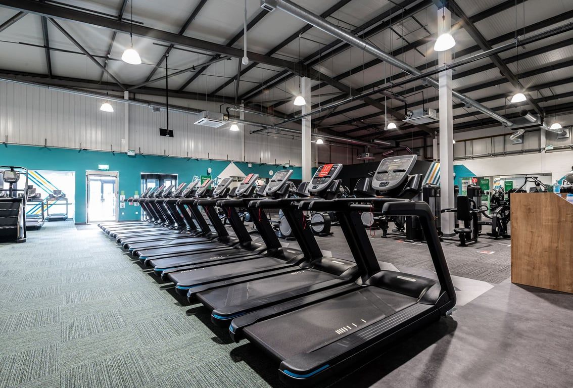 PureGym Swindon Stratton: Rows of treadmills and other cardio equipment in a well-lit gym interior.