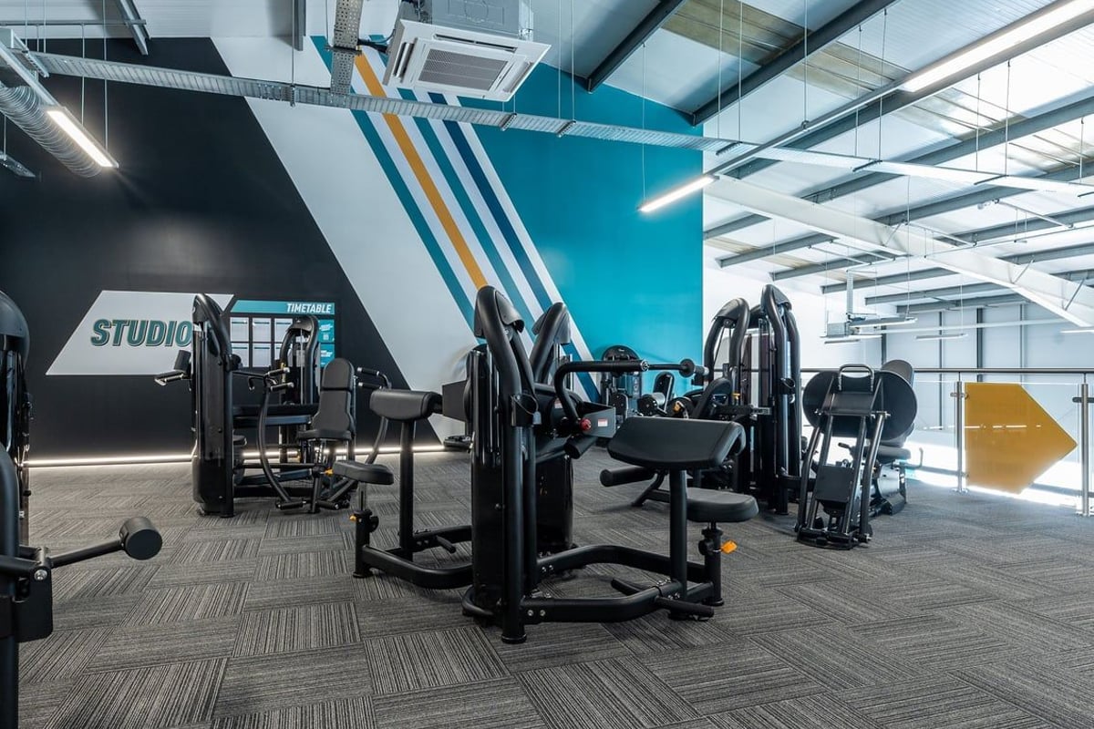 PureGym Crewe Grand Junction Retail Park: Studio with weight machines, benches, mirrors, and teal accent walls.