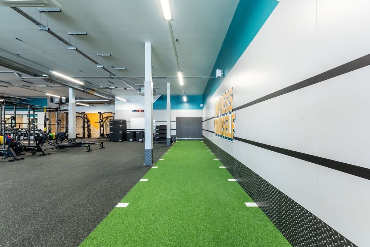 PureGym Crewe Grand Junction Retail Park: Weightlifting area, green turf runway, exercise machines, mirrored walls.