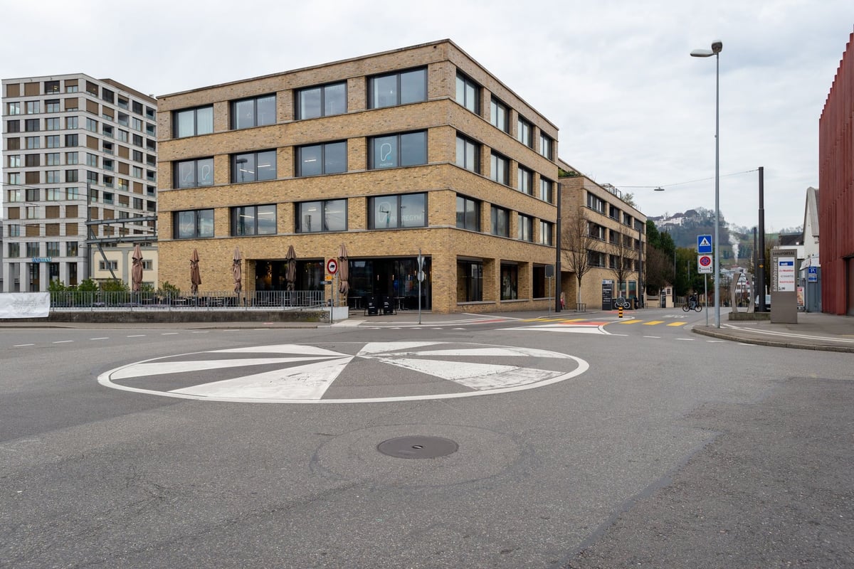 PureGym Lenzburg : Vue extérieure d'un bâtiment PureGym avec portes d'accès et marquages au sol.