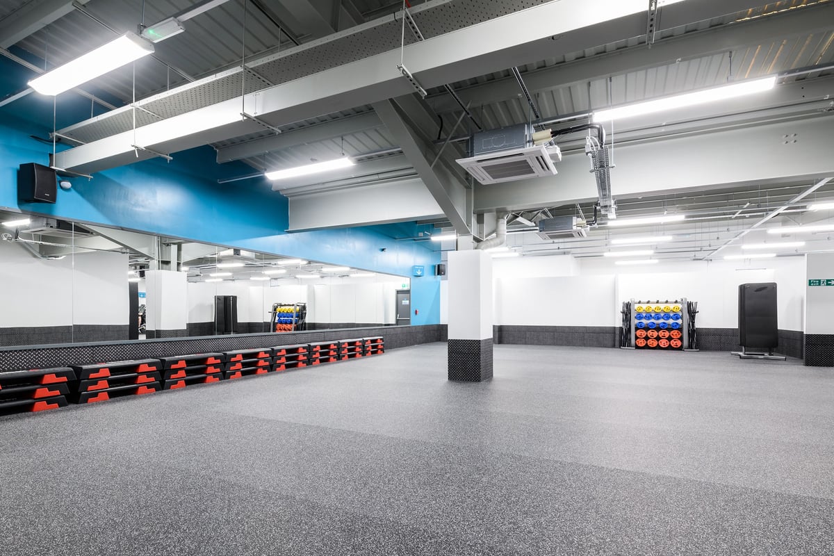 PureGym Aberdeen Wellington Circle: Open gym space with rubberized flooring, weight racks, wall padding, and mirrored walls.