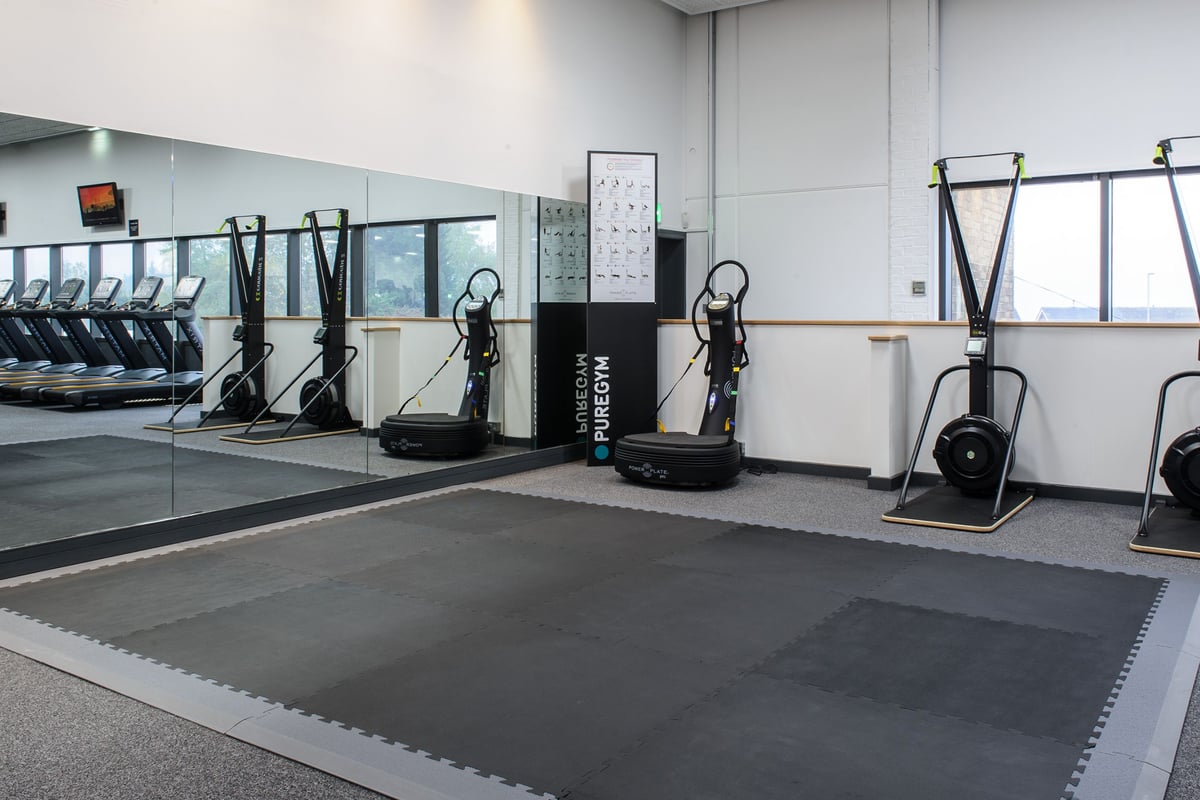 PureGym Bedford Heights: Rows of aerobic machines, resistance bands, and cushioned flooring in a bright studio.