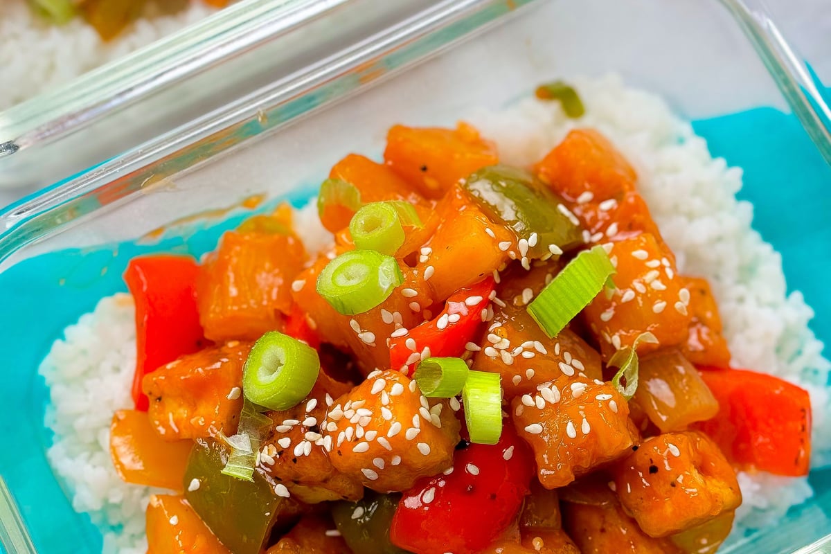 Sweet and sour tofu with red and green peppers, spring onions, and sesame seeds on rice