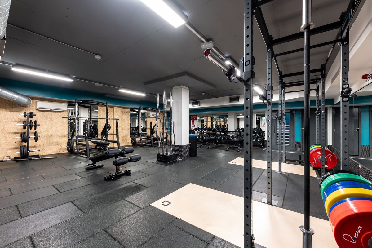 PureGym London Putney: Squat racks, weight plates, benches, barbells, and rubberized flooring in a gym setting.