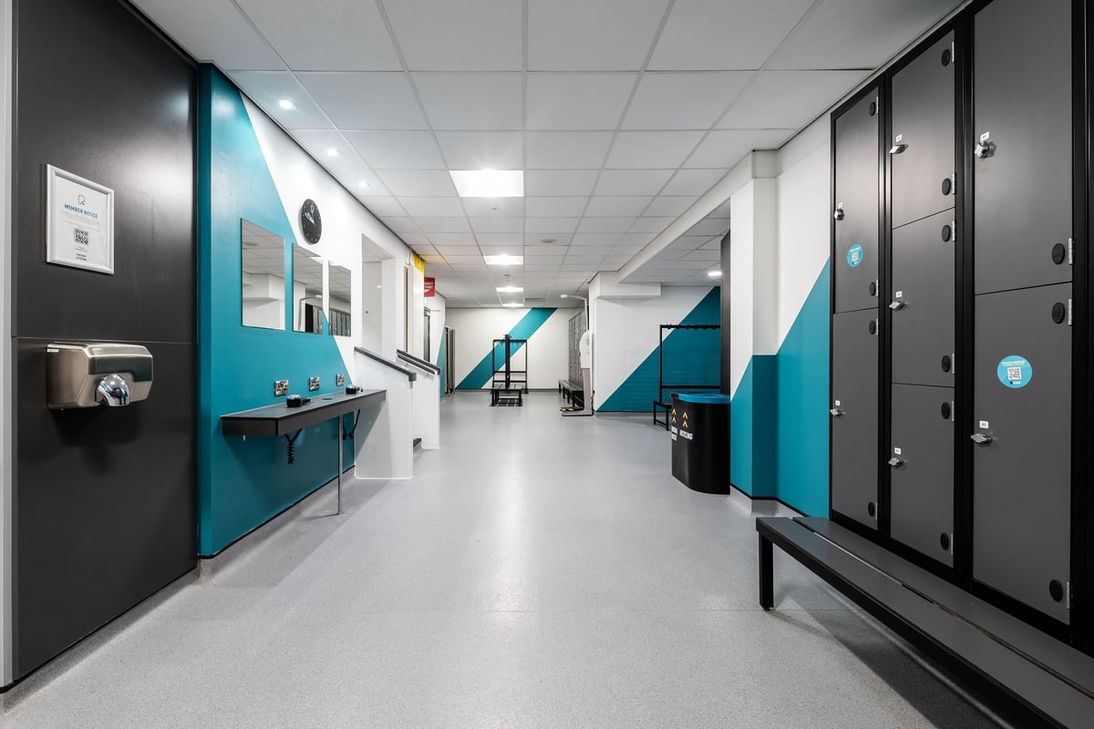 PureGym Southampton Bitterne: Lockers, benches, and tiled hallway in a facility's changing area.