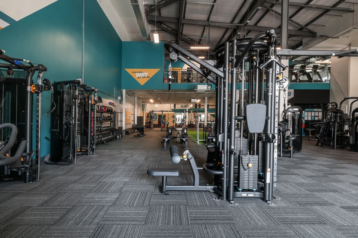 PureGym Bishop Auckland: Strength training area with weight machines, cable crossovers, benches, and rubberized flooring.