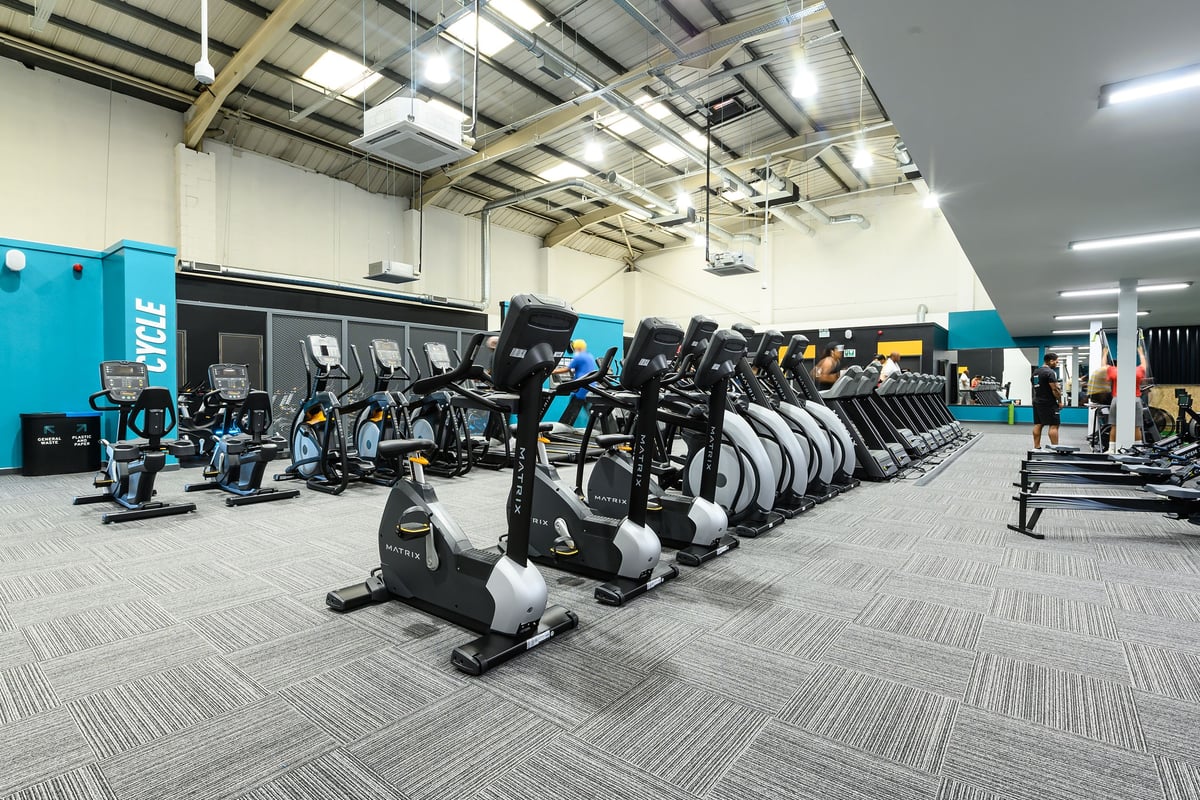 PureGym London Hayes: Rows of stationary bikes, ellipticals, treadmills, and free weights inside a spacious gym.