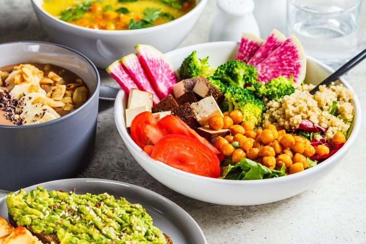 Bowl of salad with chickpeas, broccoli, quinoa, tomato, tofu, and watermelon radish slices