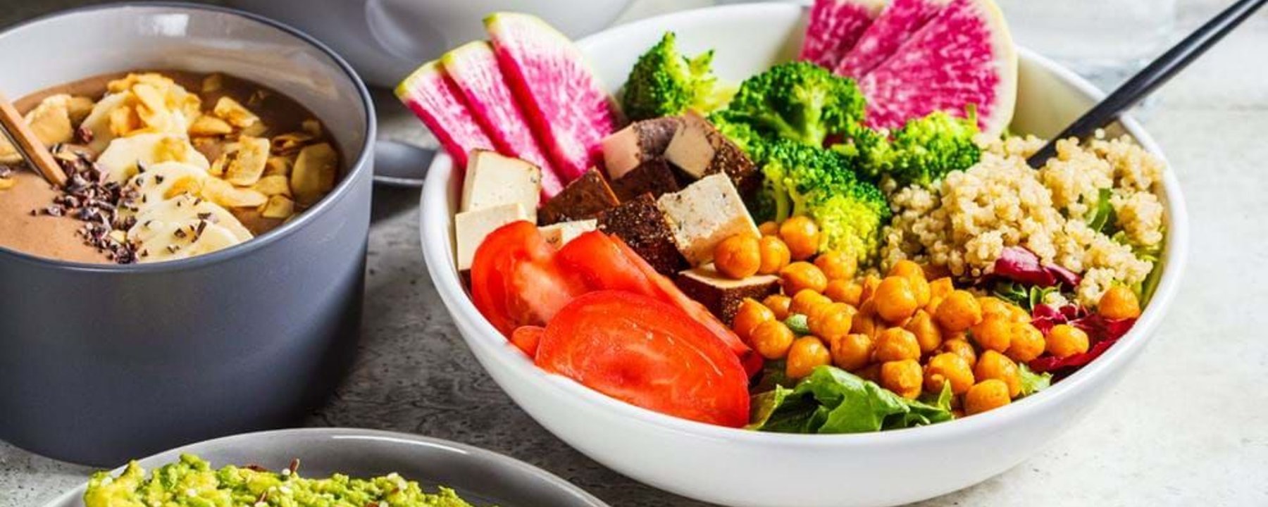 Bowl of salad with chickpeas, broccoli, quinoa, tomato, tofu, and watermelon radish slices