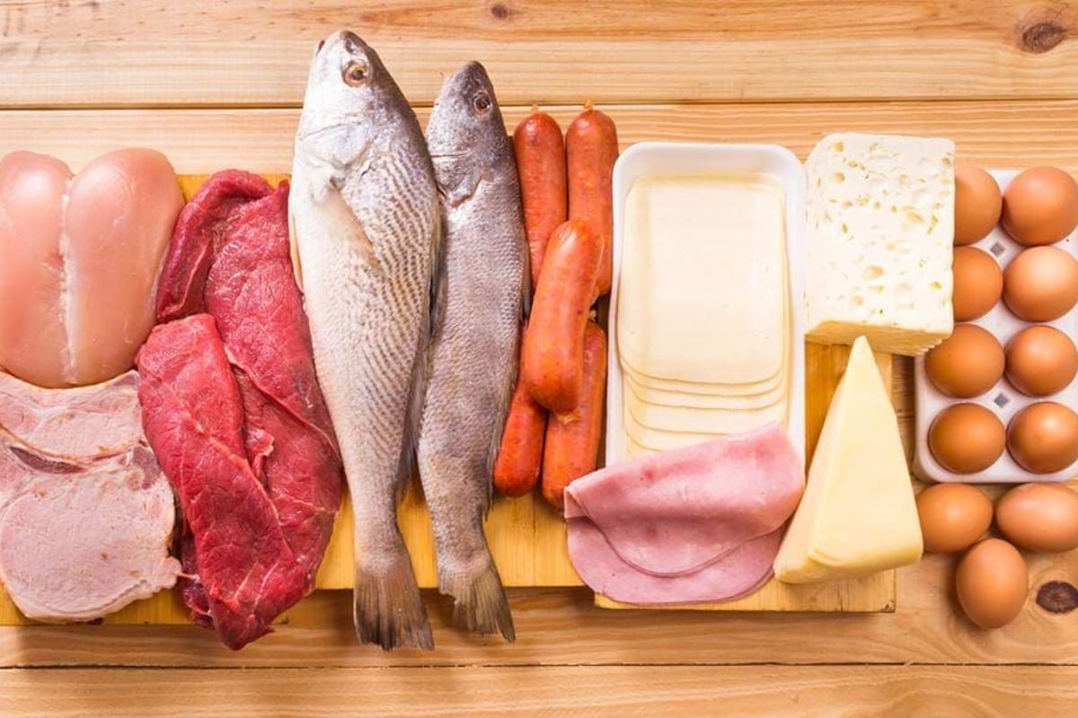 Raw chicken, beef, pork, fish, sausages, sliced cheese, ham, cheese blocks, and eggs on wo