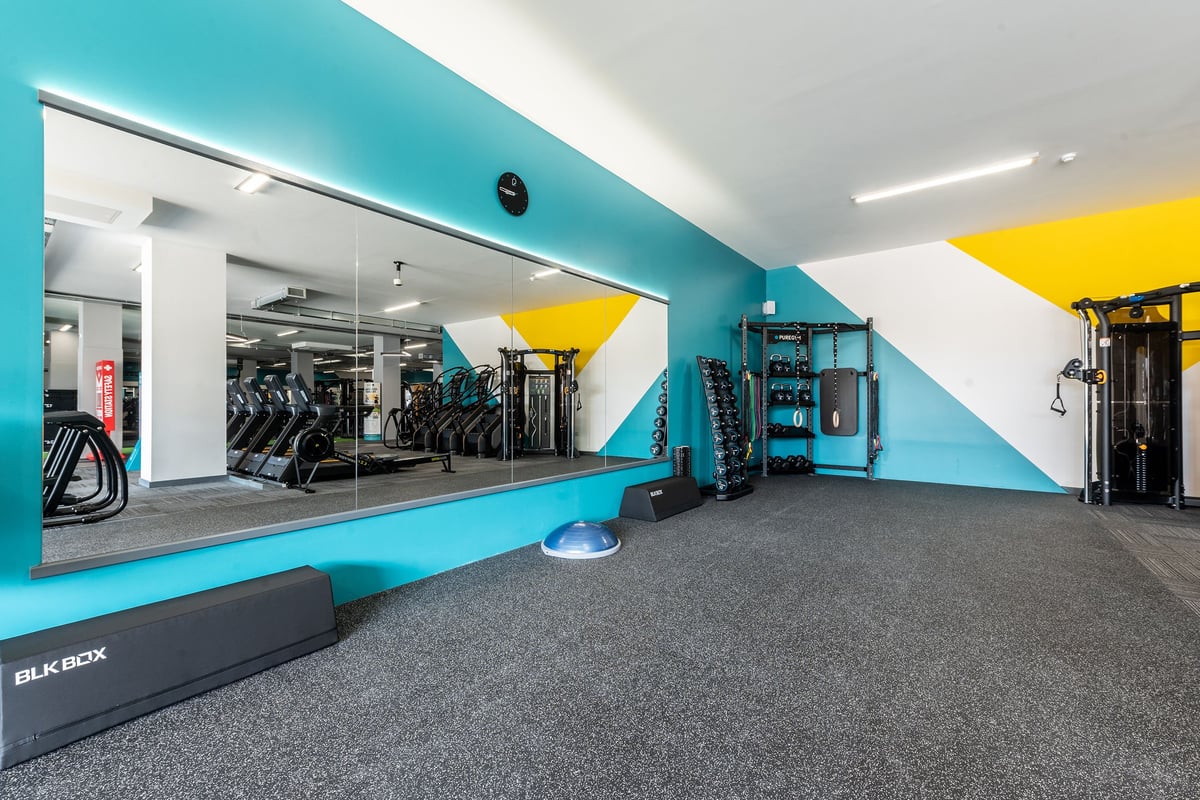 PureGym Coalville: Rows of treadmills and weight machines within a teal and yellow colour scheme.