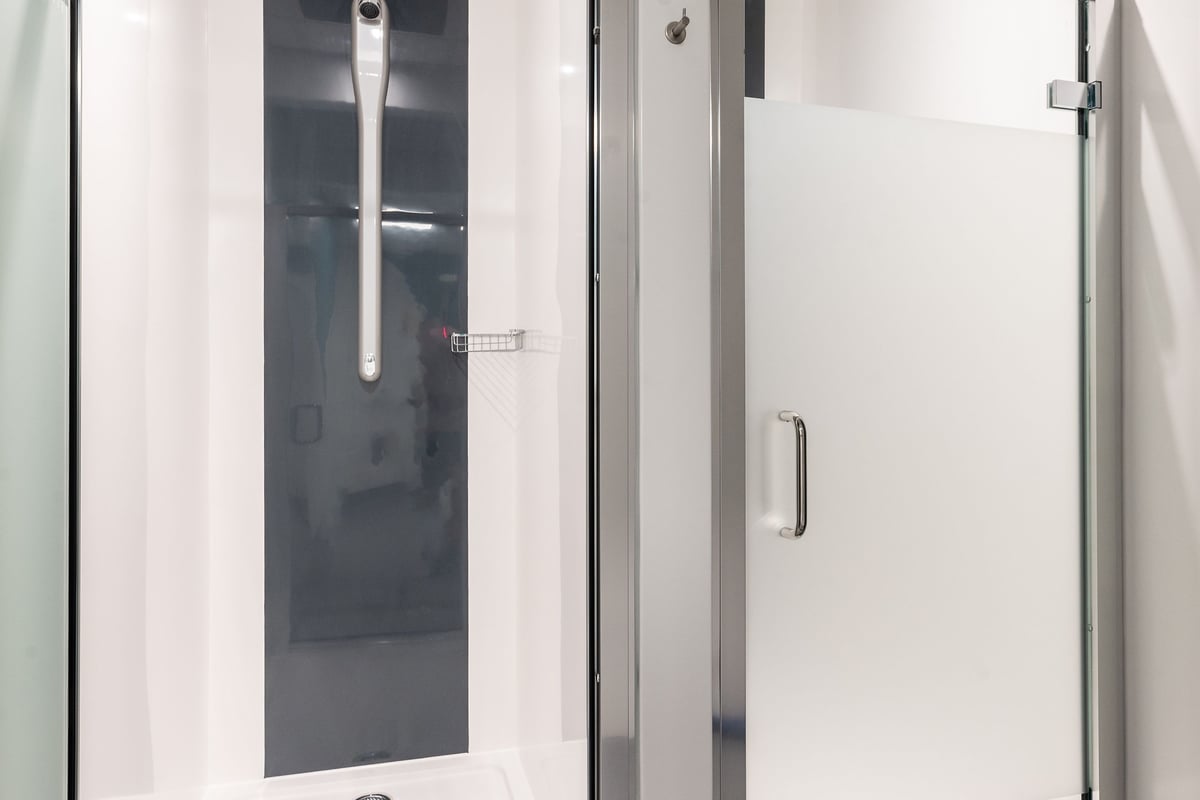 PureGym Sittingbourne: Glass-enclosed shower area with tile flooring and shower stalls.