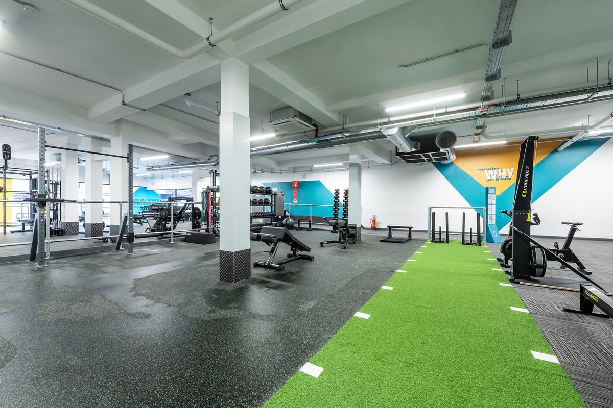PureGym Brentwood: Industrial gym with weight racks, barbells, turf area, rubberized flooring.