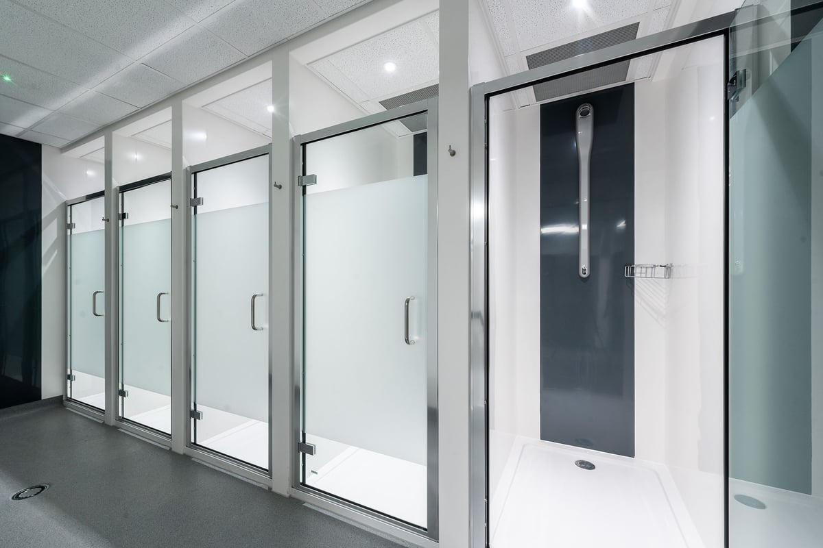 PureGym Ashford Warren Retail Park: Rows of frosted glass shower stalls or changing cubicles with doors.