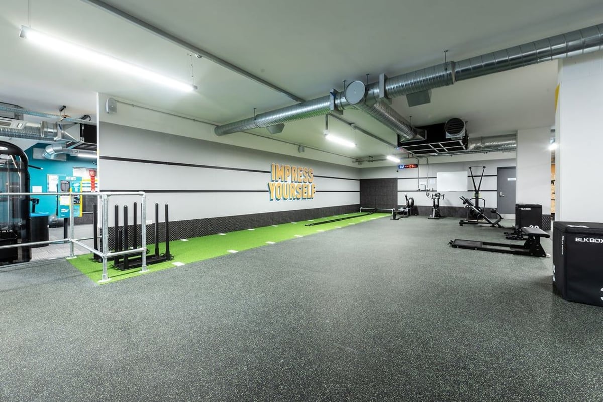 PureGym London Swanley: Large open gym space with weight racks, turf area, rubberized flooring, and equipment along walls.