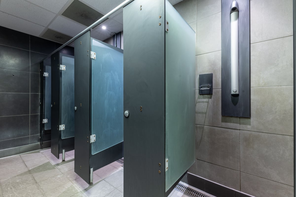 PureGym London Edgware: Changing cubicles, grey lockers, tiled floor, overhead lighting.