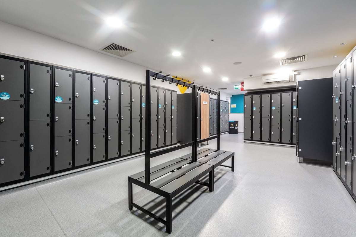 PureGym London Limehouse: Rows of lockers, benches in a spacious, well-lit changing room interior.