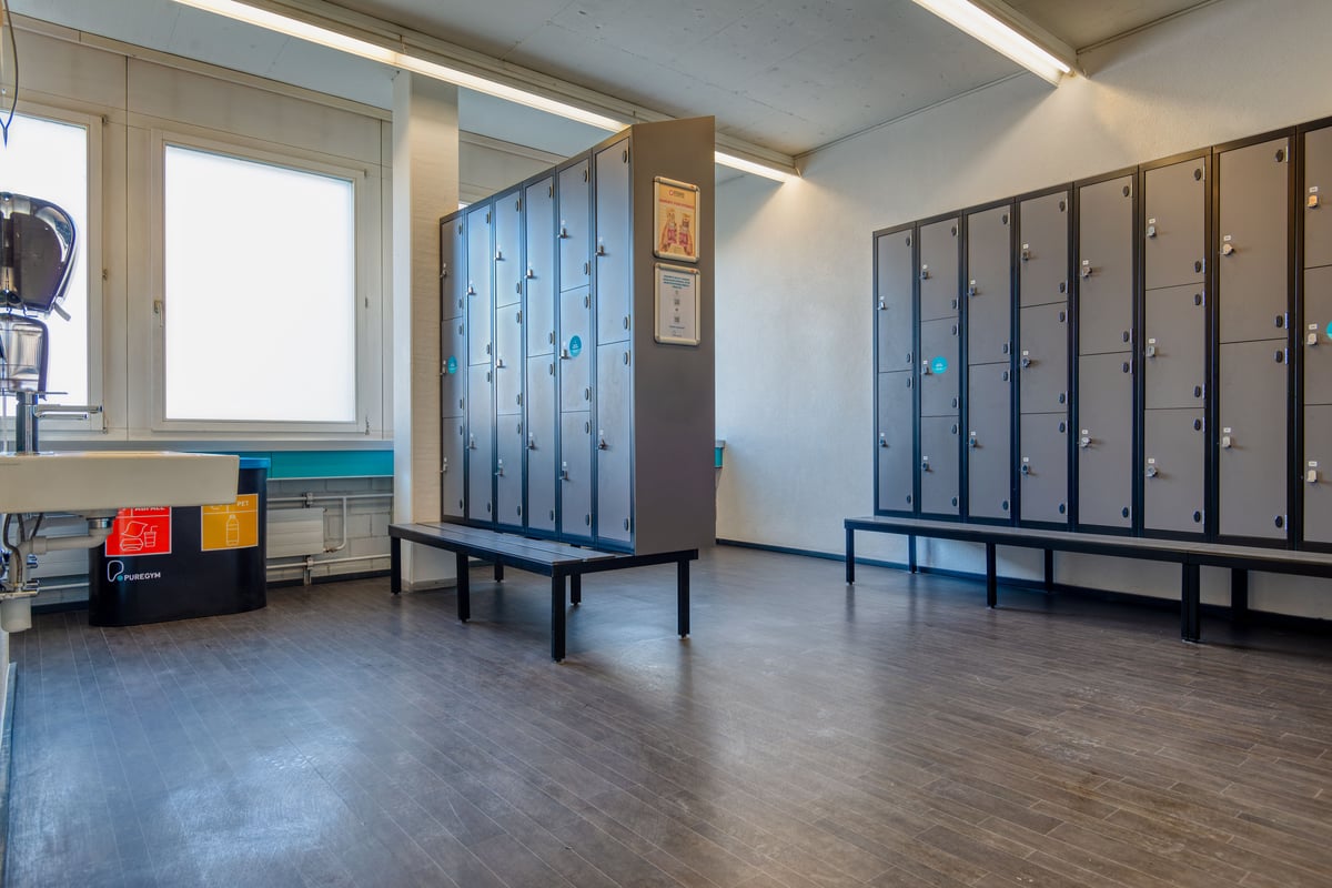 PureGym Wetzikon: Umkleideraum mit Bänken, Schränken und Bodenfliesen.