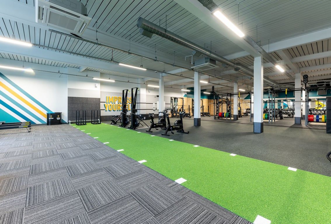 PureGym Glasgow Milngavie: Resistance training area with squat racks, weight plates and artificial turf.