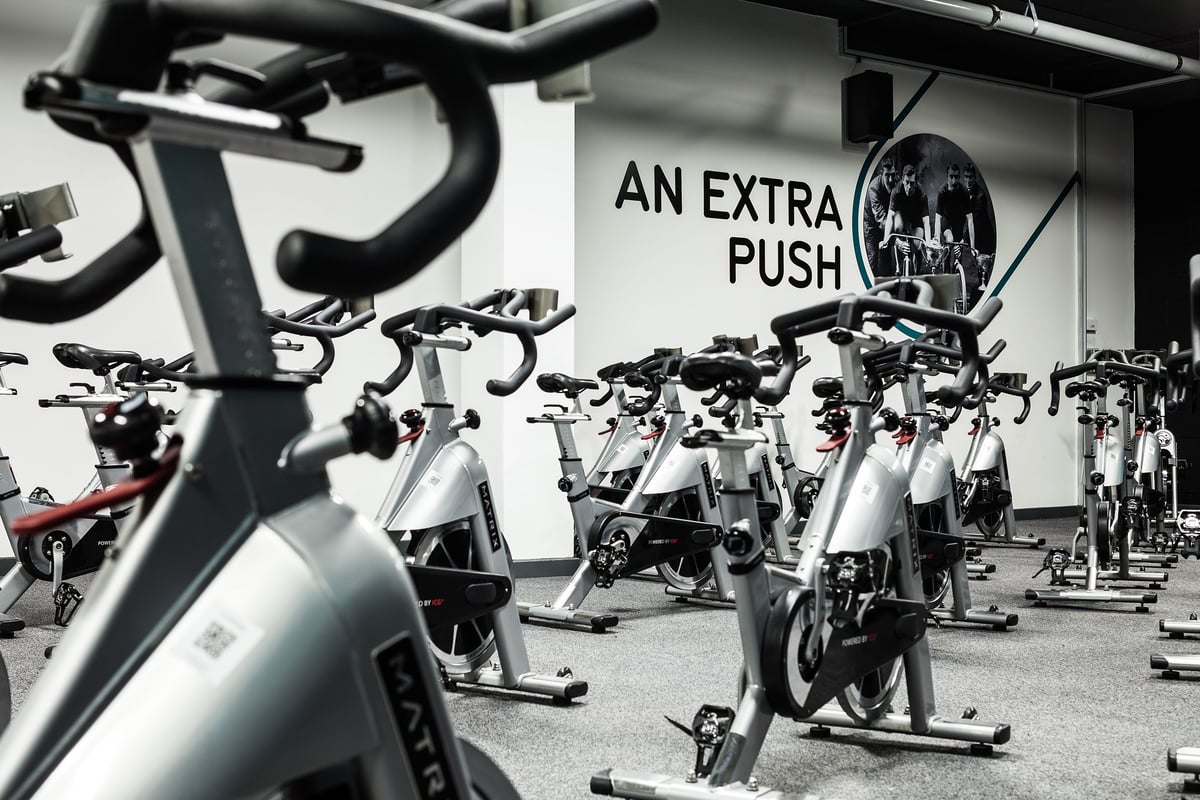 PureGym Altrincham: Rows of stationary bikes, motivational signage in a fitness studio interior.