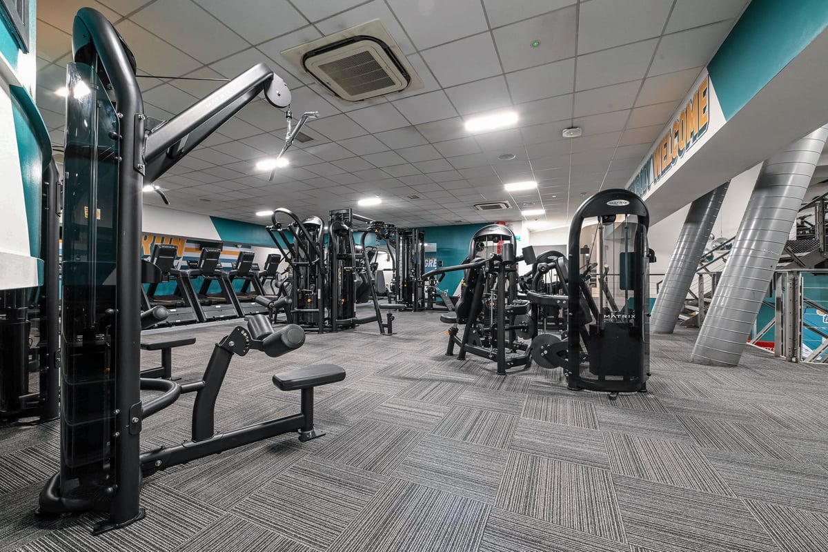 PureGym London Piccadilly: Gym interior with weight machines, benches, rubberized flooring, and teal accents throughout.
