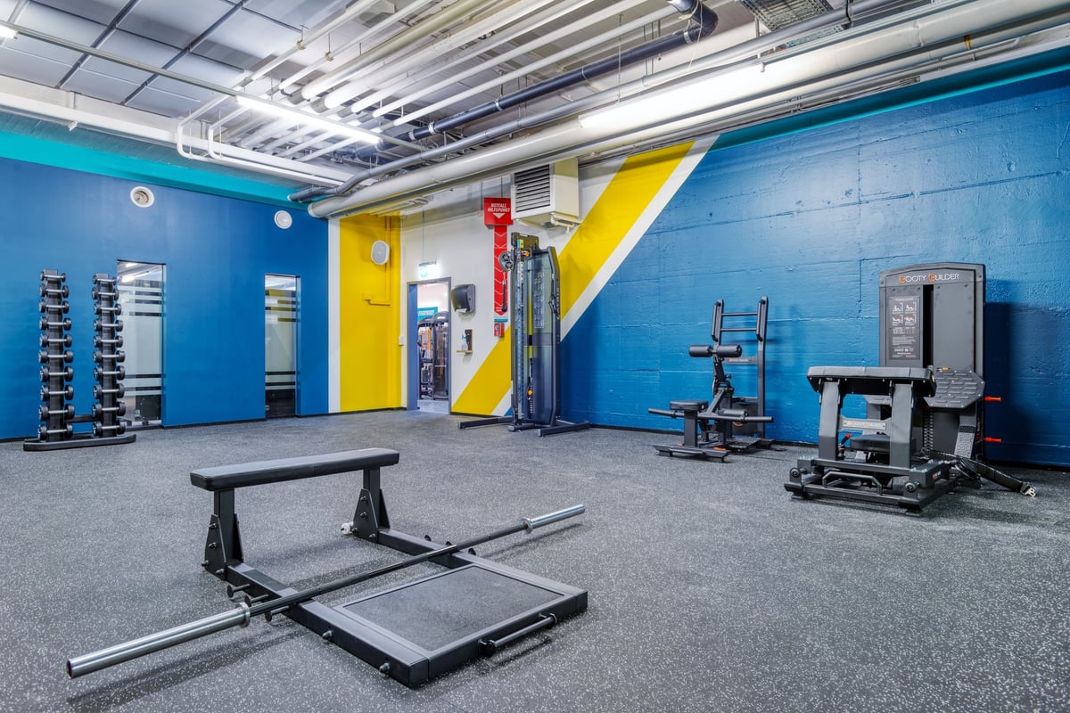 PureGym Dübendorf: PureGym functional training area with weight benches, squat racks, and cable machines.
