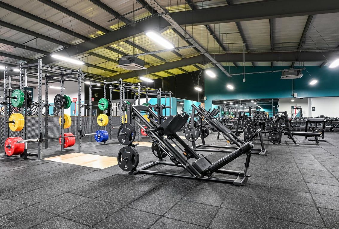 PureGym Canterbury Sturry Road: Weights racks, barbells, benches and rubberized flooring in a brightly-lit workout facility.