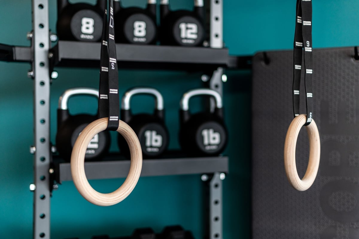 PureGym Yate: Wooden gymnastic rings hanging from racks alongside kettlebells and weight plates.