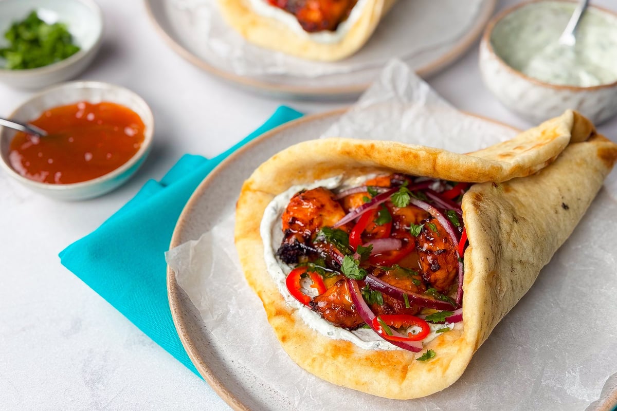 Folded flatbread filled with chicken, red onion, peppers and herbs on a plate