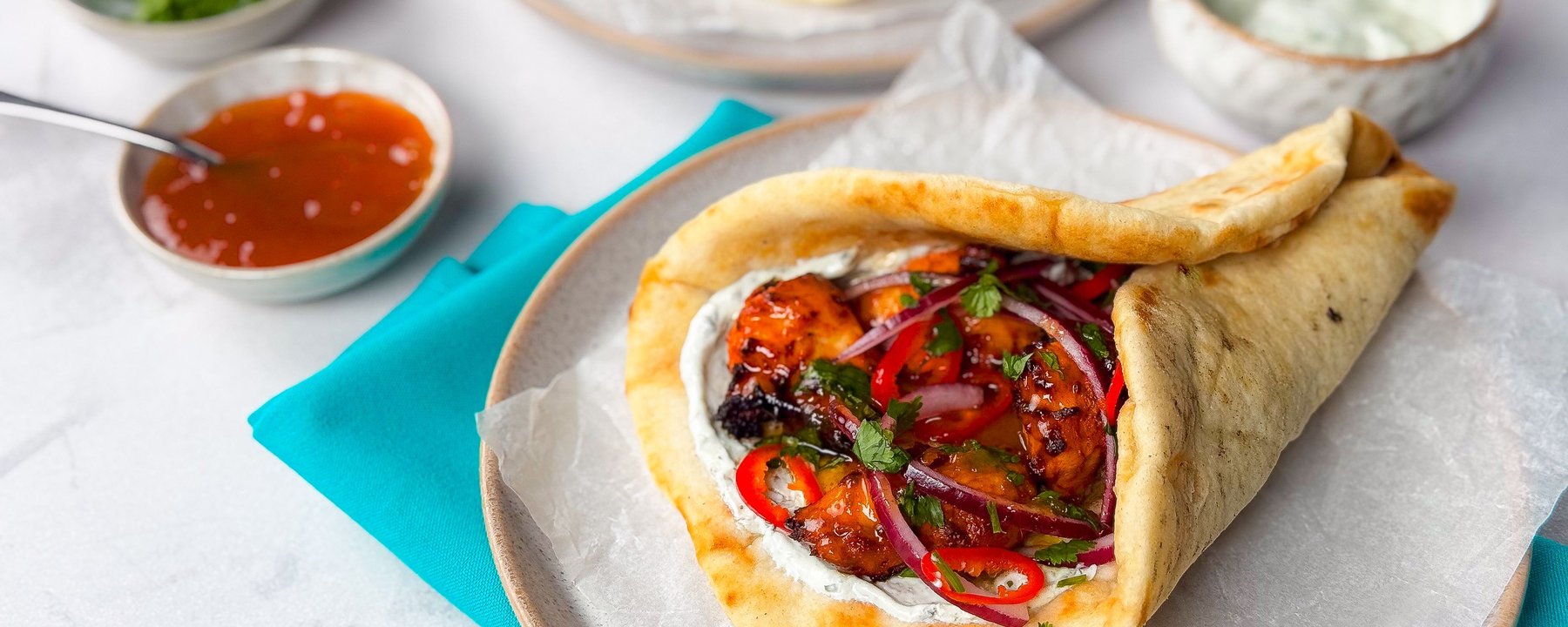 Folded flatbread filled with chicken, red onion, peppers and herbs on a plate