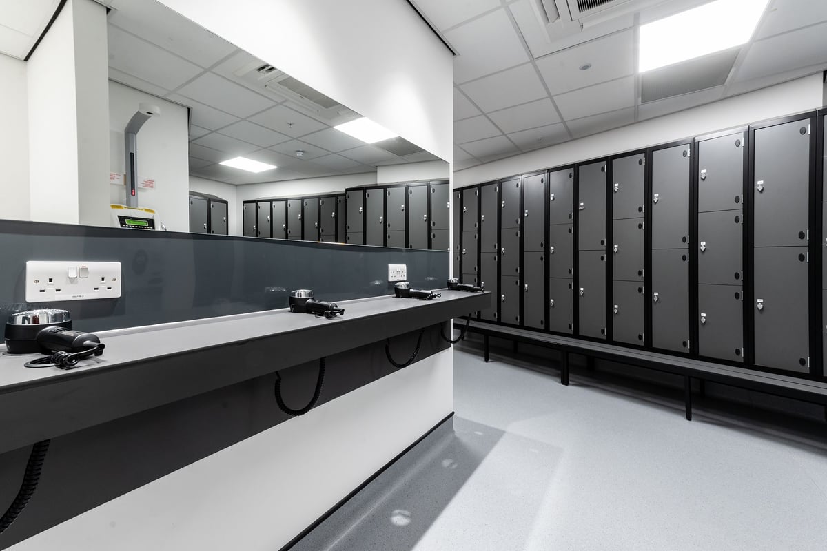 PureGym London Hoxton: Rows of lockers, benchtop counter, and pristine flooring indicating a changing room facility.
