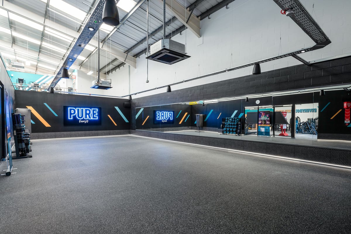 PureGym Cannock Orbital Retail Park: Brightly lit gym interior with Pure branding, dark flooring, and promotional posters.