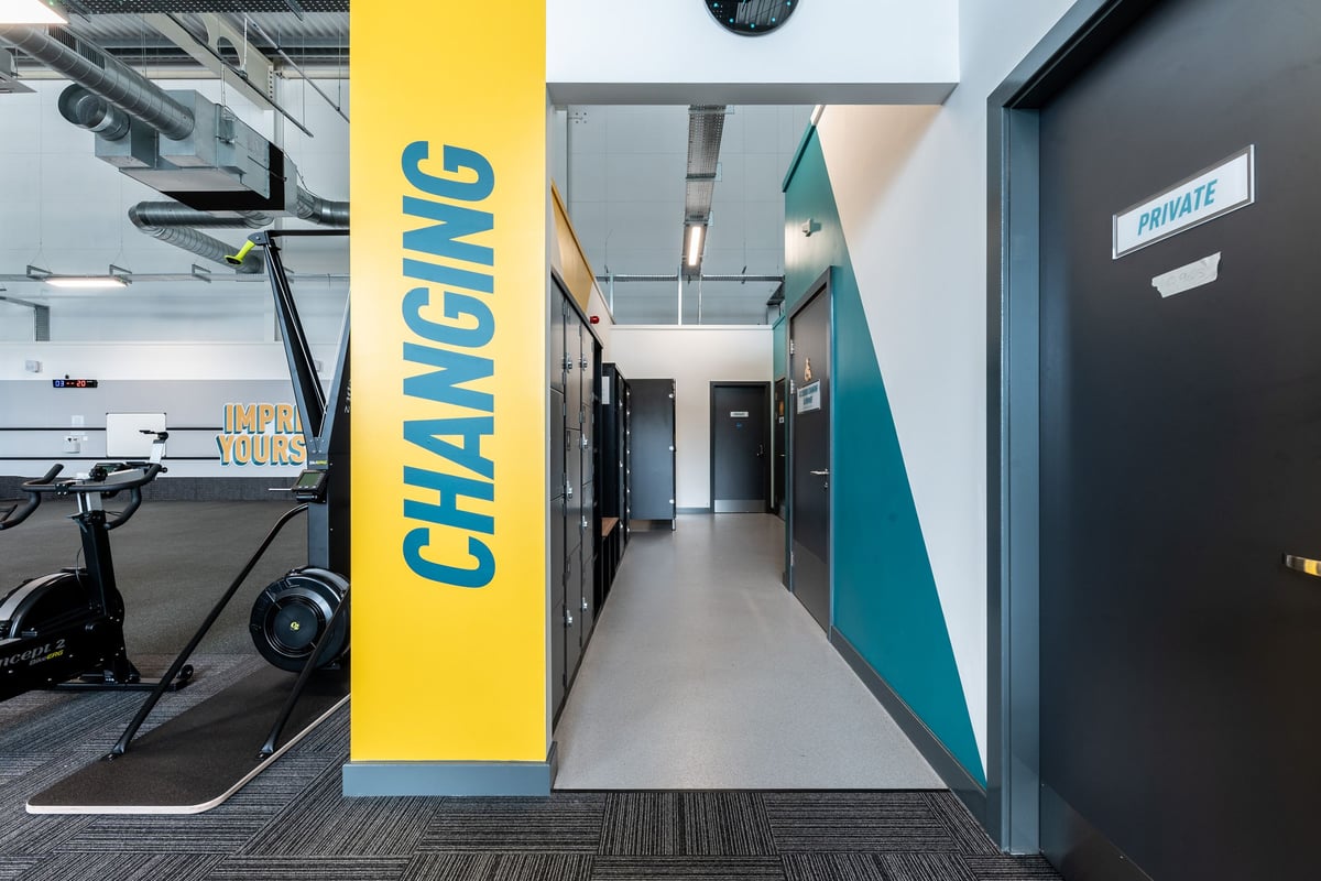 PureGym St Ives Cambridgeshire: Long corridor with fitness equipment storage, changing room access.