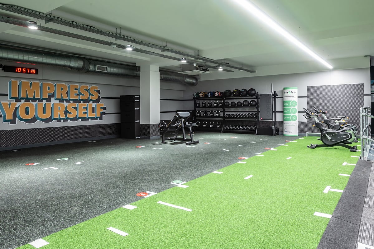 PureGym London Twickenham: Weight racks, kettlebells, green turf area, rubberised flooring, motivational wall signage.