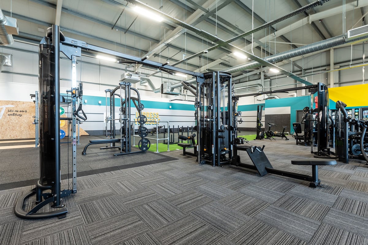 PureGym Stamford: Functional training area with weight racks, cable machines, benches, and rubberized flooring.