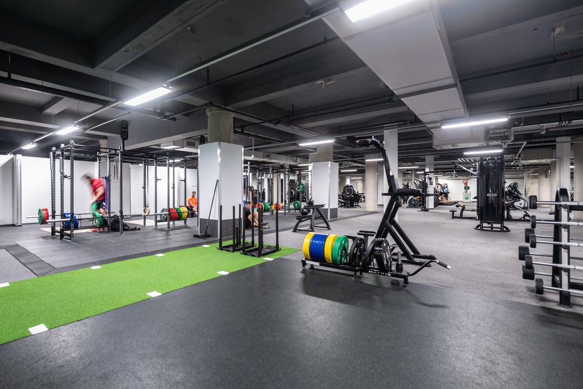 PureGym Liverpool Central: Gym with racks, free weights, green turf area, and rubberized flooring in industrial-style space.