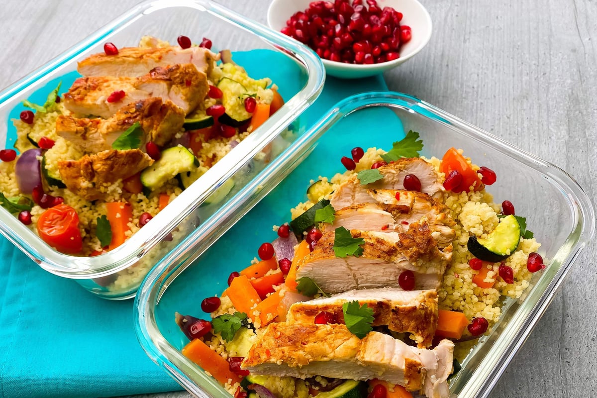 Sliced chicken breast on couscous with courgette, peppers and pomegranate seeds