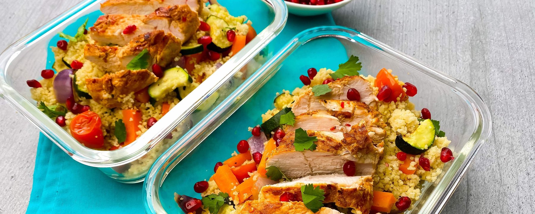 Sliced chicken breast on couscous with courgette, peppers and pomegranate seeds