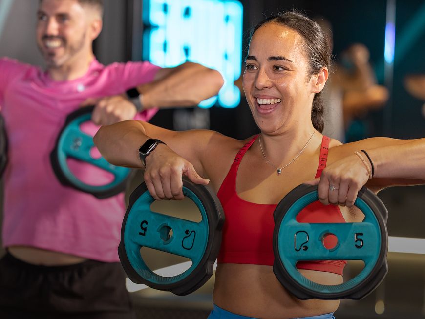 Feel PureGym Good: Upright Row female class participant lifting 2x 5kg plates