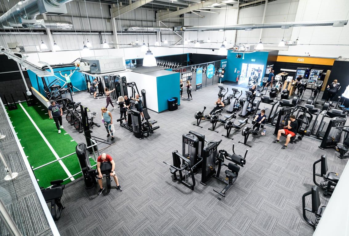 PureGym Folkestone: Large gym space with resistance machines, free weights, turf area, and workout equipment.