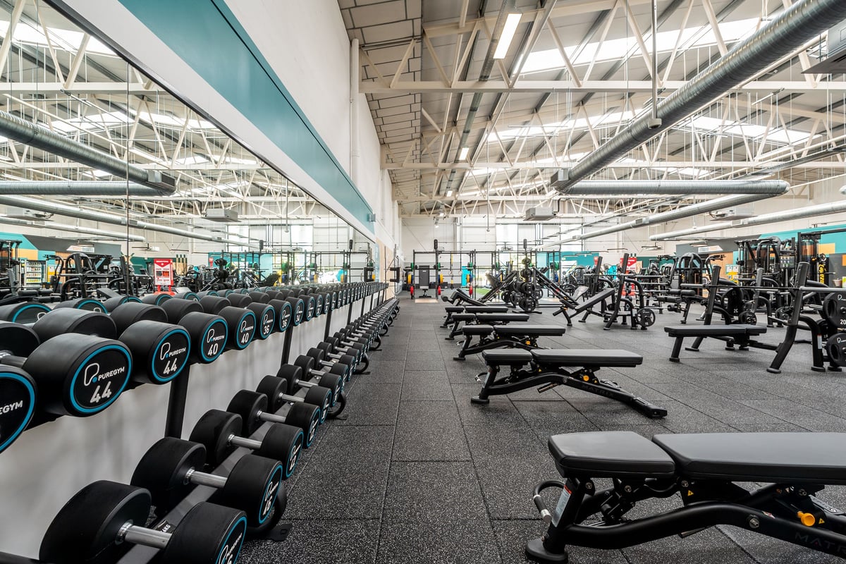 PureGym Bridgend: Free weights, benches, weight plates, and rubberized flooring in a large gym space.