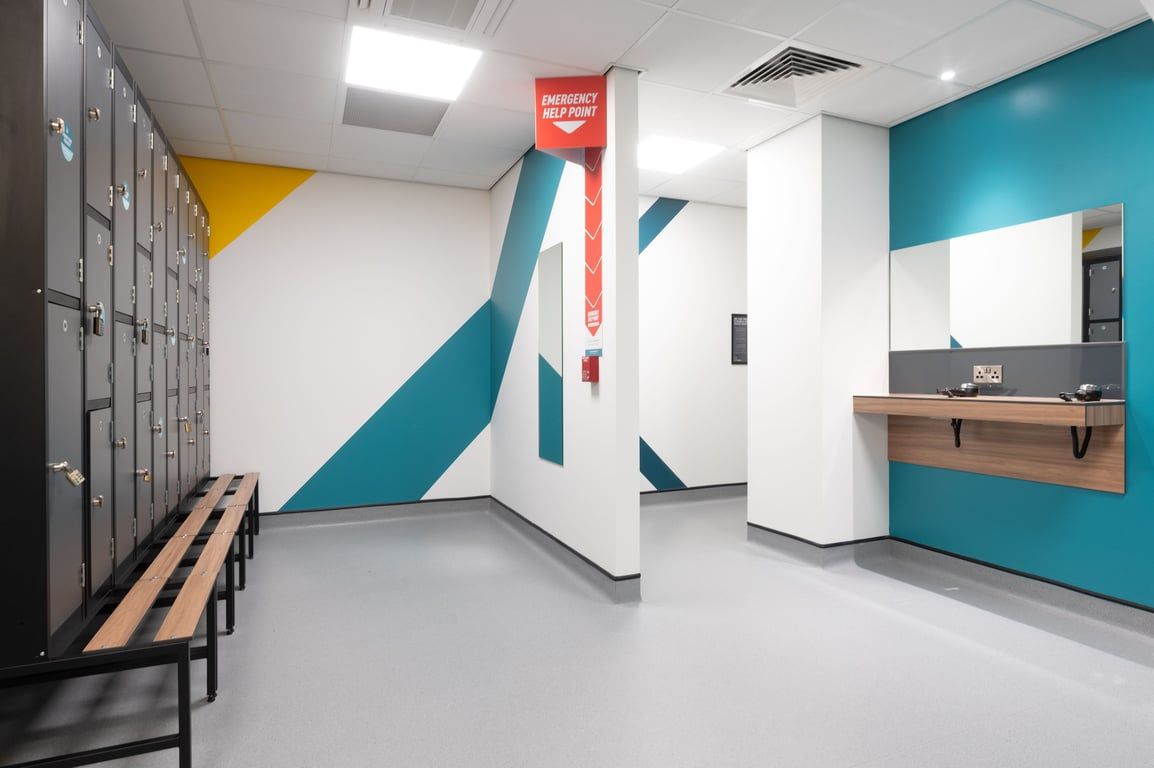 PureGym Plymouth Derriford: Locker room with benches, lockers along the walls, and rubberized flooring.