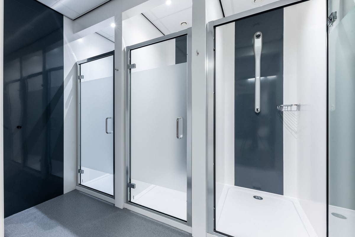 PureGym Redditch Ringway: Shower room stalls with frosted glass doors and metal frames.