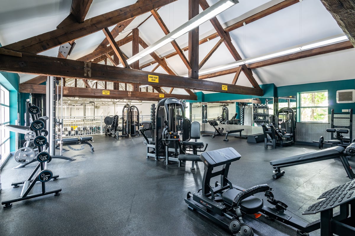 PureGym Northwich: Gym with weight machines, free weights, benches and exposed wooden beams.