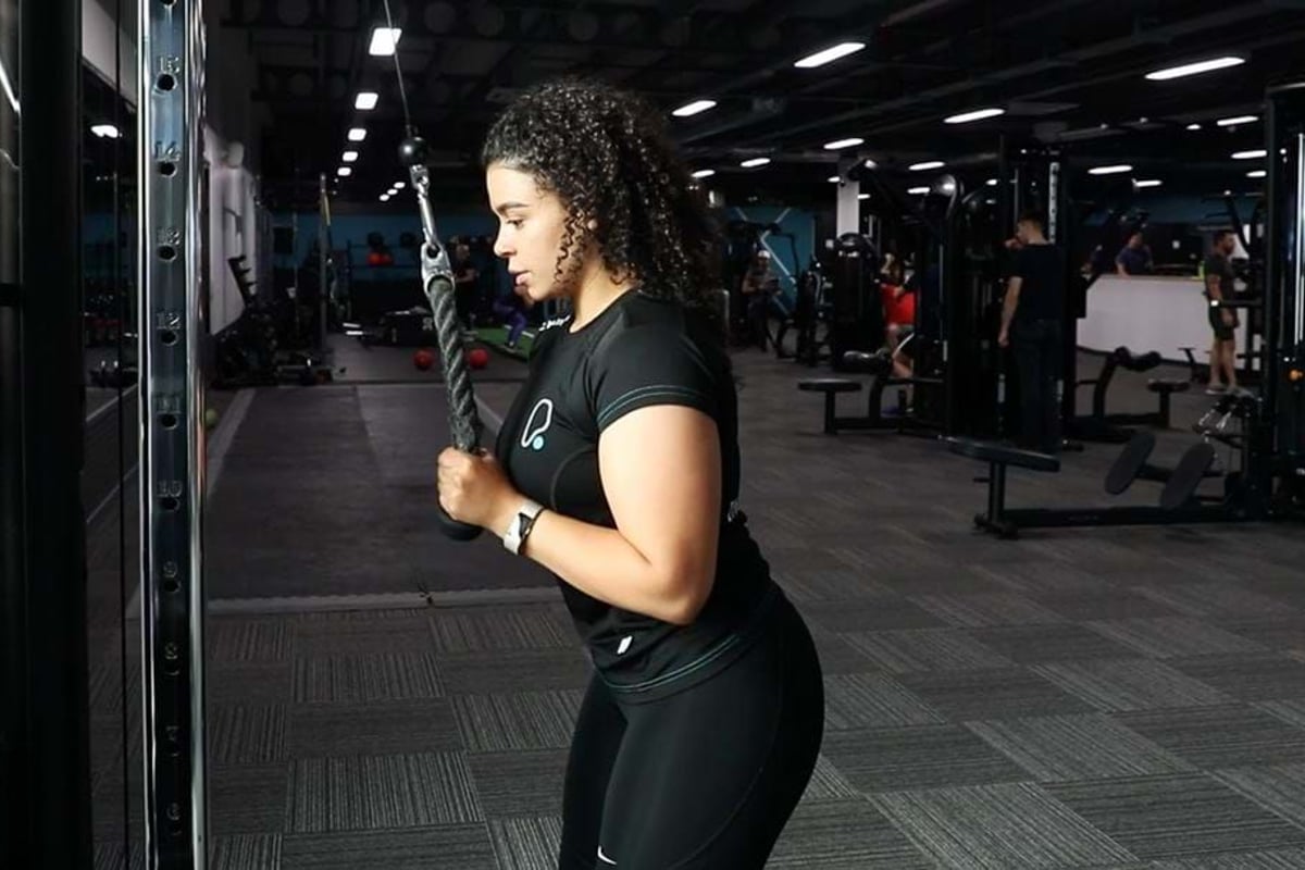 Woman exercising tricep pushdown with rope attachment in a gym