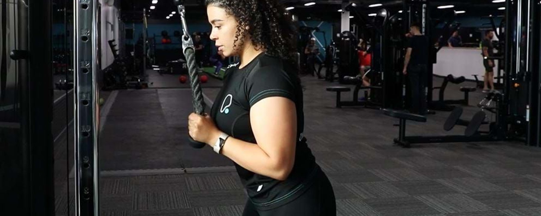 Woman exercising tricep pushdown with rope attachment in a gym
