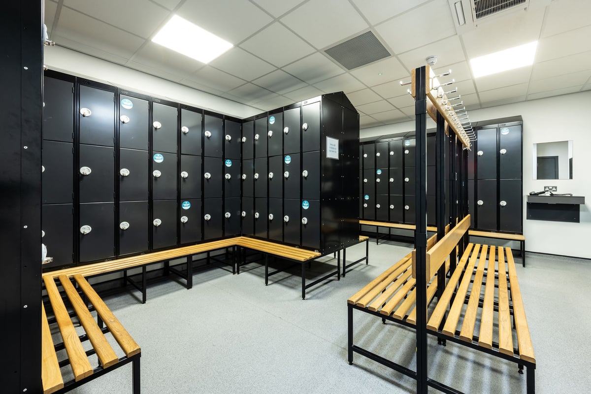 PureGym Motherwell: Lockers, benches, tiled flooring in gym changing room area.