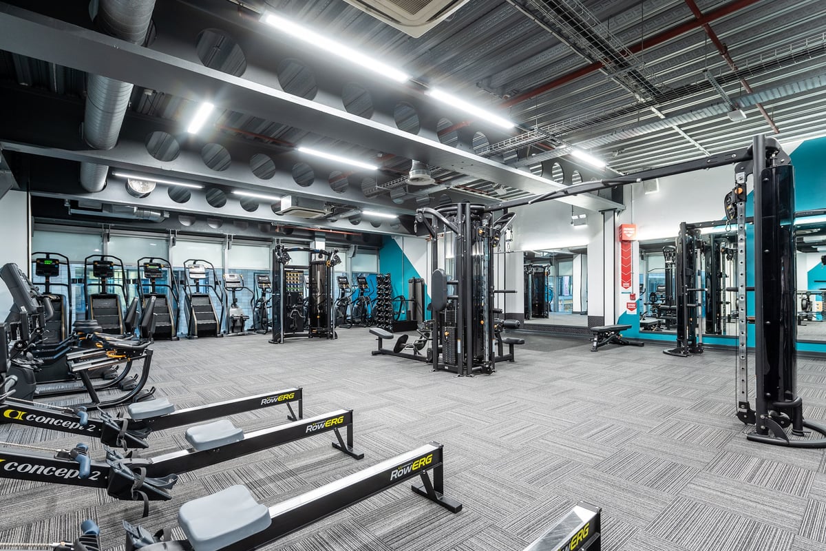 PureGym Manchester Spinningfields: Strength training area with weightlifting racks, benches, and dumbbells.