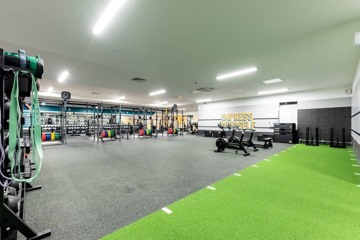 PureGym Bangor Wales: Resistance machines, free weights, benches, turf area, and rubberized flooring in a gym setting.