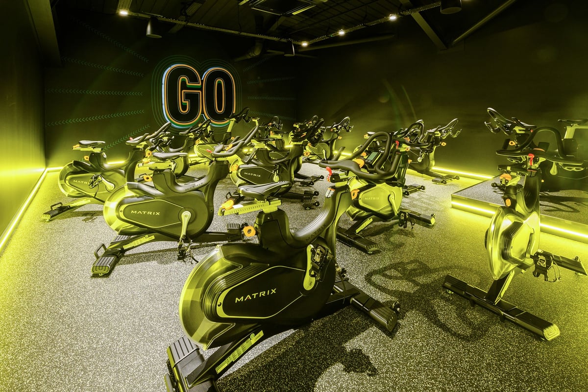 PureGym South Ruislip: Rows of stationary exercise bikes with neon 'Go' signage in a dimly lit space.